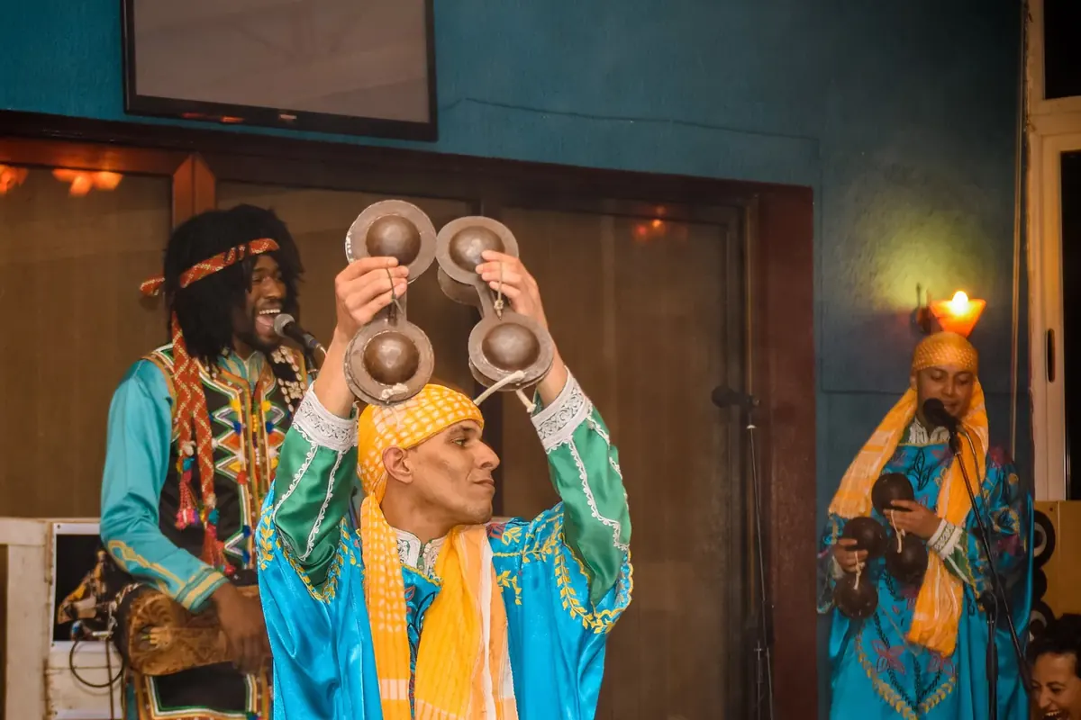 Gnawa musicians in traditional dress playing qraqeb castanets
